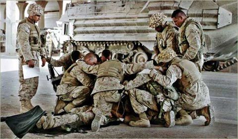 Deployed U.S. servicemen pause in prayer before a mission.